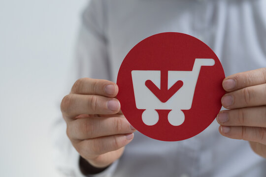 Close up of hands holding a red circle with a shopping cart and download arrow symbol