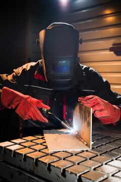 Welding sparks illuminate the dark workshop