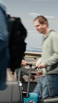 Vertical video Upset woman in airport scolding man after bumping trolley into her while hurrying to catch plane. Angry tourist yelling at traveler for bashing her luggage in busy departure terminal