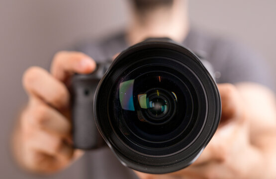 Professional photographer holding a camera lens, focused and ready to capture a moment.