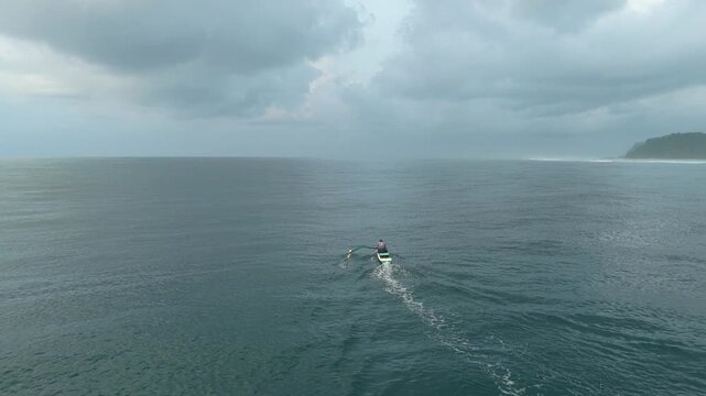 Aerial view of a fisherman paddling an outrigger canoe near pandawa beach