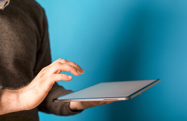 Person using tablet against a vibrant blue backdrop, perfect for technology concepts and modern desi © vegefox.com
