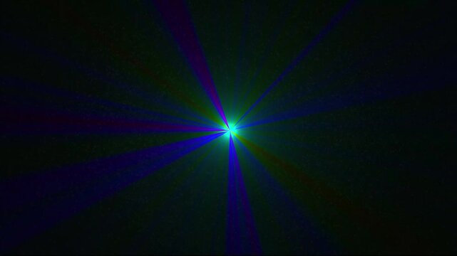 A vibrant multi-colored starburst with a bright green core emits blue and magenta light rays outward into a dark, speckled background, creating a and energetic abstract light effect