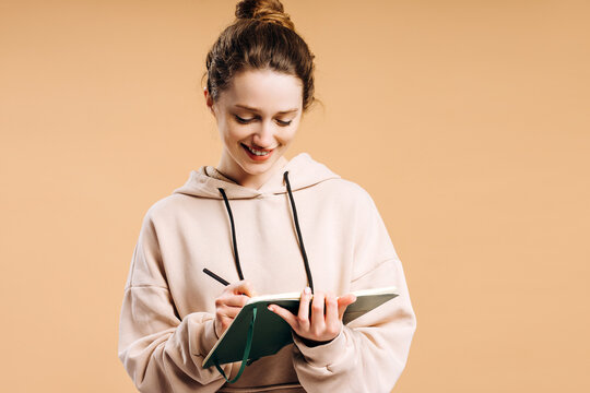 Young woman writing notes in green journal smiling