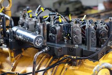 A close-up shot of a hydraulic transmission control valve unit mounted on a Komatsu heavy machinery engine. © Jumain