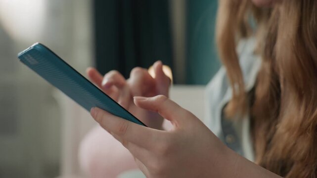 Closeup caucasian hands holding smartphone, student texting messages in cozy bedroom, soft natural light, blue phone case, focused fingertip tapping screen, relaxed home lifestyle mood, candid social