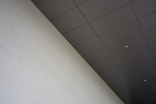 Concrete wall meeting grid ceiling with architectural detail and geometric composition