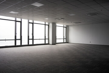 Naklejka premium Spacious modern office interior with floor-to-ceiling windows and empty carpeted space