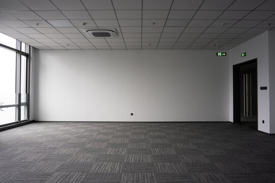 Empty modern office interior space with carpeted floor and ceiling grid lighting