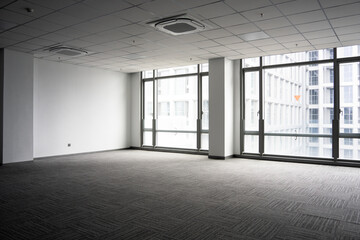Naklejka premium Spacious modern office interior with empty space, gray carpet, ceiling panels, and large glass windows
