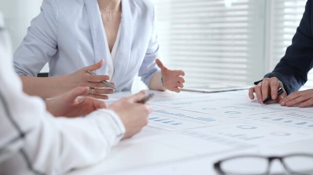 Businesswoman signing important contract documents at a meeting. Confirming agreement and partnership details while colleagues show support