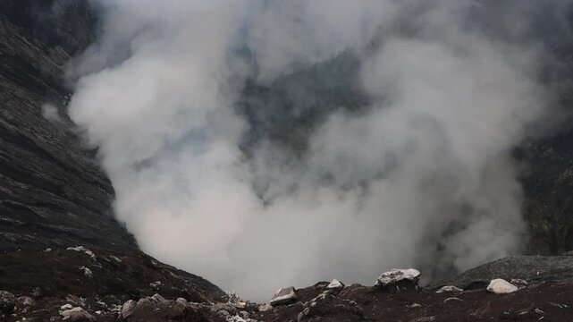 A dramatic volcanic landscape dominated by massive clouds of thick white steam rising from an active crater Mount Bromo in East Java, Indonesia  