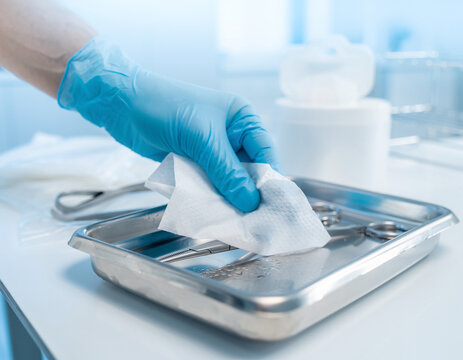 Hand using a sanitizing wipe to clean a medical instrument in a sterile environment for patient safety.