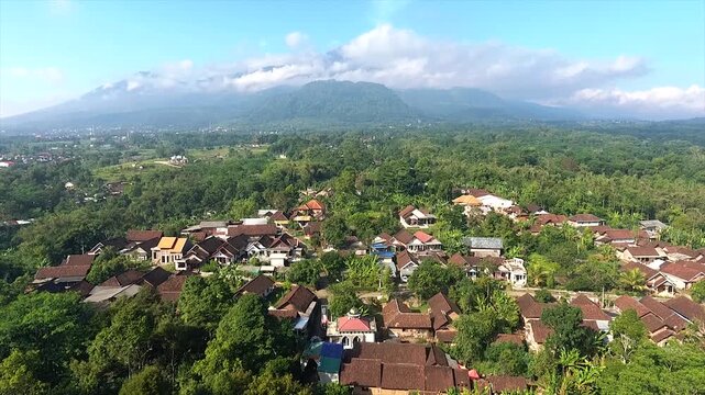 Aerial view of a traditional Indonesian village nestled at the foot of a majestic mountain.