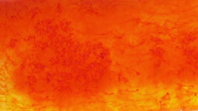 Red and orange colored flowing liquid in macro, dirty water texture