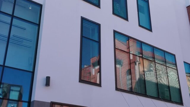 Modern corporate office building with glass facade integrated with revitalized historic red brick industrial architecture, low angle view of urban development and adaptive reuse.