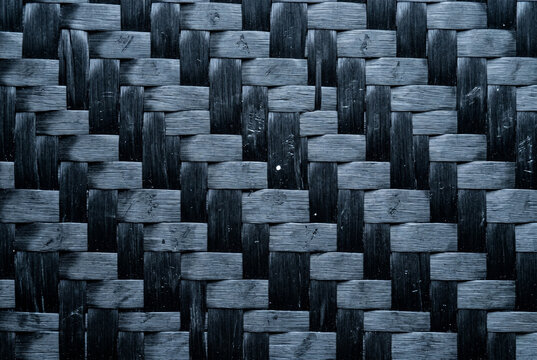 Extreme macro of matte carbon fiber on a high-tech mobility frame. Hard raking light emphasizes the 3D relief of the 3K twill weave, showing authentic micro-pits and technical scratches.