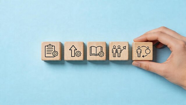 Business management concept wooden cubes with symbols for planning growth education teamwork and interaction hand placing last block on blue background
