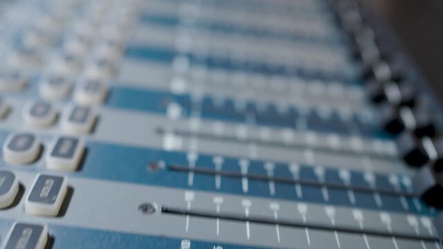 Close-up of Professional Audio Mixing Console Faders in Sound Studio. Detailed view of a professional digital audio mixer with sliding faders and buttons. Horizontal orientation