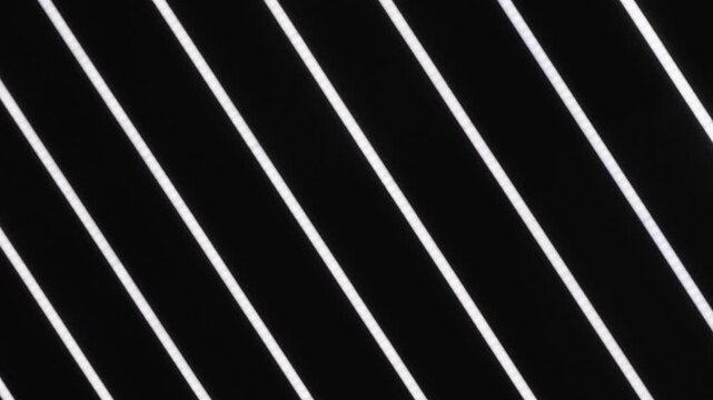 Contemporary interior ceiling featuring linear LED lamps. Minimalist geometric design light with glowing white diagonal lines against a dark background