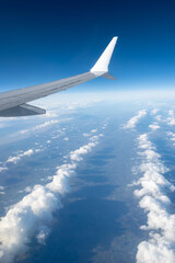 Obraz premium Airplane wings extend above white clouds, providing clear view of atmospheric layers and sense of altitude during the flight, air transportation