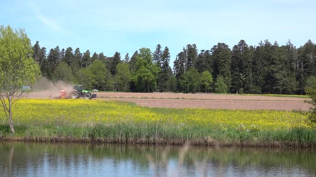 Ein Traktor f&auml;hrt &uuml;ber einen Acker und bearbeitet den Boden mit Staubaufwirbelungen