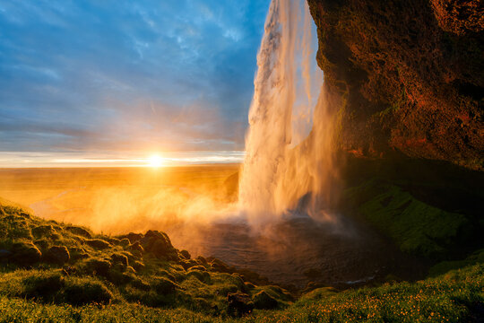 Seljalandsfoss waterfall with golden sunset behind falls in summer Iceland
