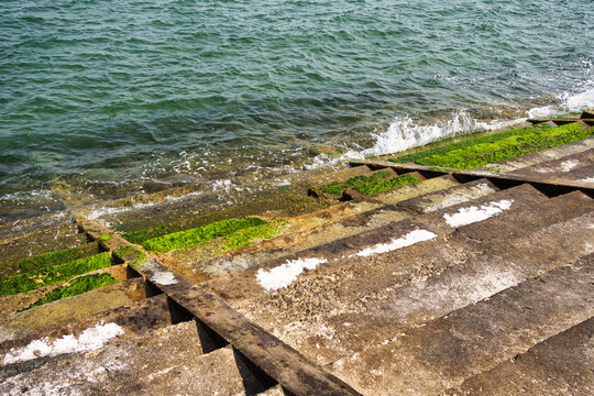 Coastal stone stairs with green moss and ocean waves