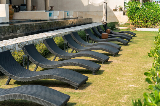 Elegant black woven loungers by poolside in tranquil outdoor setting