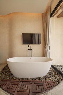 Luxury minimalist bathroom interior with bathtub and TV in sandstone style