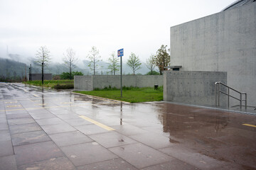Fototapeta premium Wet pavement in a modern architectural plaza after rain with distant mountains and fog