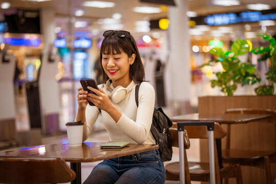 Business traveler relaxing in airport lounge with coffee and laptop, waiting for flight departure, symbolizing modern travel, work mobility, and professional lifestyle on the go.
