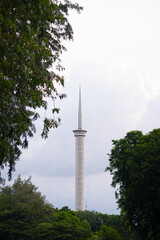 Obraz premium The tall, iconic minaret of Istiqlal Mosque in Jakarta seen through lush green trees under a bright sky
