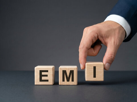 professional businessman hand arranging emi wooden blocks on dark background for banking and loan repayment concept