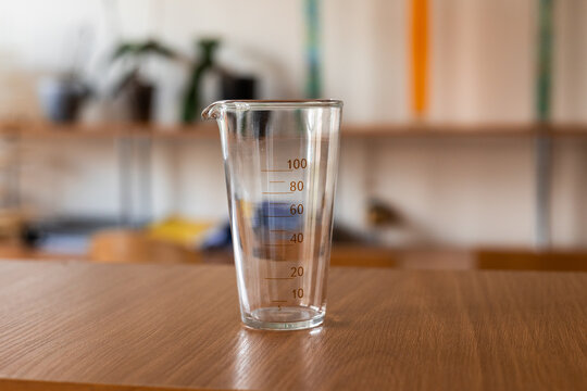 A clear measuring cup placed on a wooden table, showcasing precise measurement markings for cooking and baking.