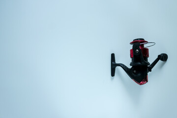Naklejka premium Modern spinning fishing reel isolated on white background, featuring durable build and sleek red-black design, ideal for sport fishing, outdoor recreation, and fishing gear concepts.