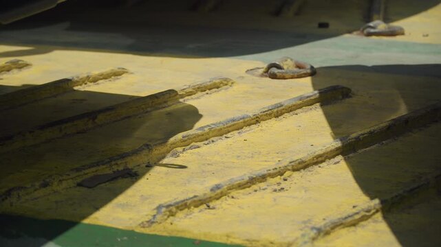 Yellow meal on conveyor belt, dramatic shadows cast across ridged rows of coarse grain, industrial mill floor detail with bolt and shadow, sunlit contrast highlighting texture and granules,