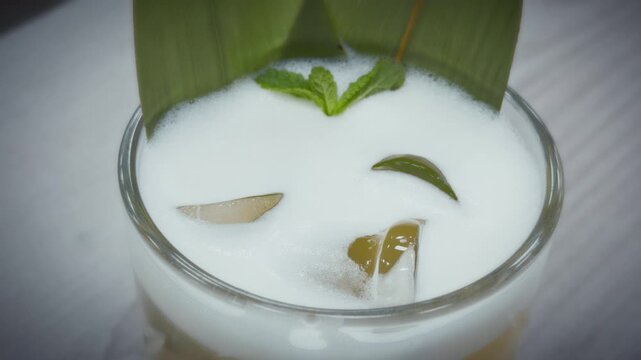 Cold refreshing mojito cocktail glass filled crushed ice, fresh mint leaves, lime slices. Condensation drops on glass, summer party drink, non alcoholic beverage, rum soda background, macro shot.