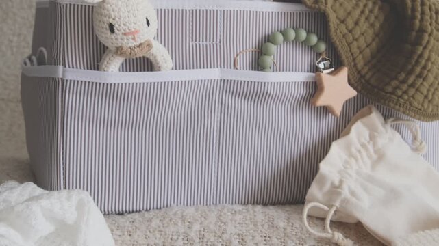 Organization of newborn baby accessories, clothes, and toys in a nursery storage caddy