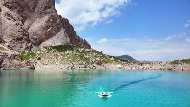 Aerial View of Boat on Open Turquoise Lake with Mountain Shore, Kyrgyzstan