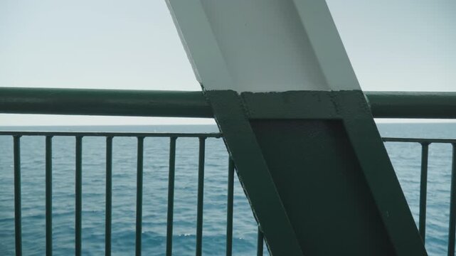 Ship deck railing overlooking calm ocean horizon, diagonal support beam framing distant water, soft teal light, gentle waves, minimal industrial texture, open sky tranquility, cinematic composition