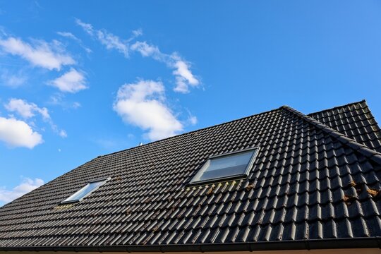 House roof with dark tiles and skylight windows