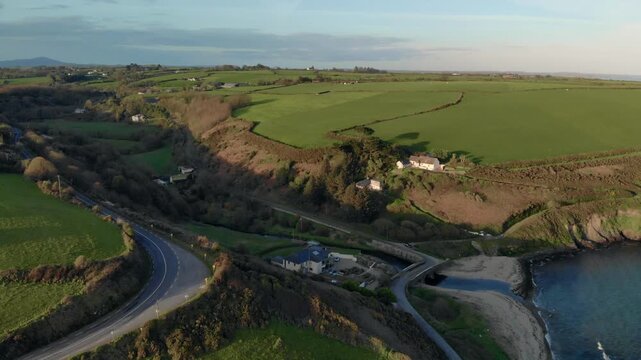 Drone glides smoothly over Irish countryside, revealing vast green fields and rugged shoreline, inspiring serenity and natural beauty, perfect for travel and wellness campaigns.