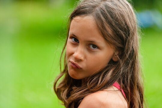grimace child gazes in close-up portrait revealing energy, enthusiasm and fun. Young girl shows funny expression with thoughtfulness and a sly grin. Kid expresses emotions