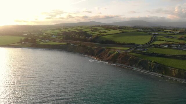 Drone glides smoothly over Irish coastline at sunset, revealing rugged cliffs and calm sea, embodying serenity and natural beauty, perfect for travel and wellness campaigns.