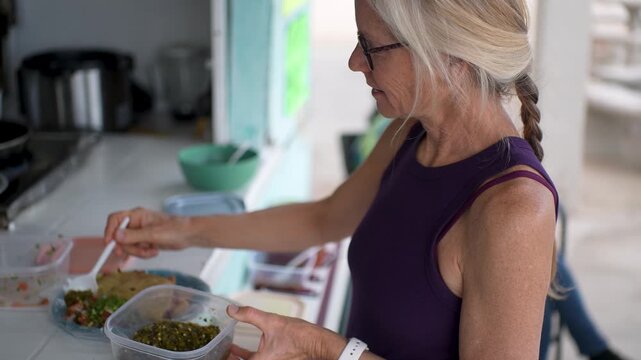 Mature woman prepares to eat shrimp tacos from a local taco stand in Baja California, enjoying the fresh ingredients and flavors.