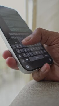 Close-up macro shot of anonymous male hands typing and chatting on a smartphone, fingers tapping a touchscreen keyboard while sending text messages in a modern digital environment. Unrecognizable pers