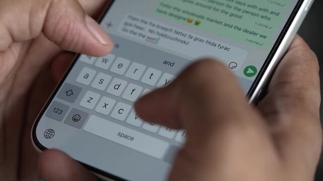 Close-up macro shot of anonymous male hands typing and chatting on a smartphone, fingers tapping a touchscreen keyboard while sending text messages in a modern digital environment. Unrecognizable pers