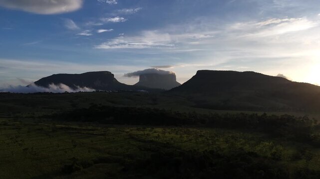 Aerial drone shot of tepuys in Canaima National Park, Venezuela, during a stunning sunset, showing golden hour light over the vast landscape, 4K