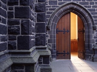 Fototapeta premium Complete heavy arched wooden church door with a stone wall copy space